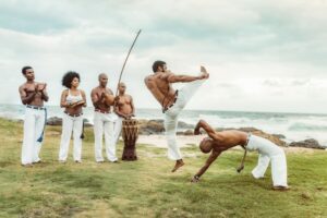 Capoeiristi brasiliani si esibiscono in una roda sulla spiaggia con musica dal vivo