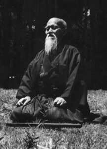 Maestro Morihei Ueshiba in meditazione in seiza all'aperto